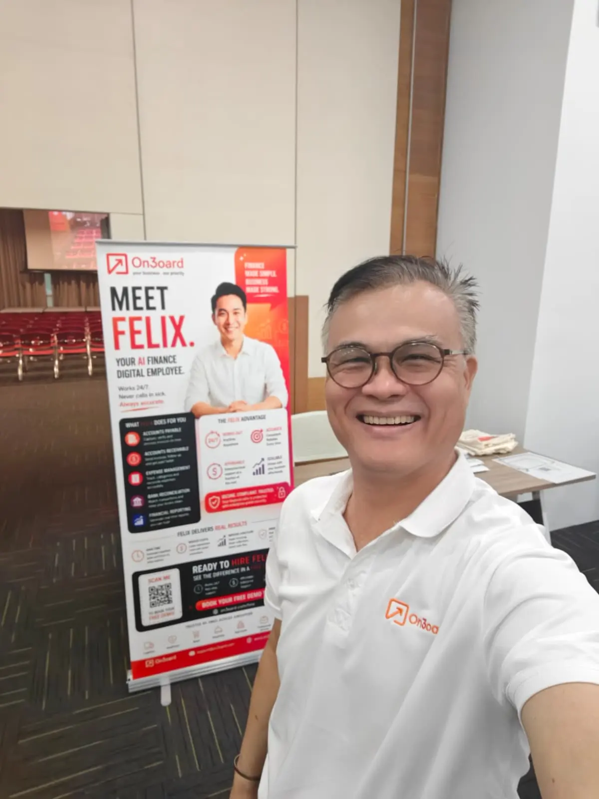 Roy Chin smiling next to the On3oard Meet Felix banner at Booth 2