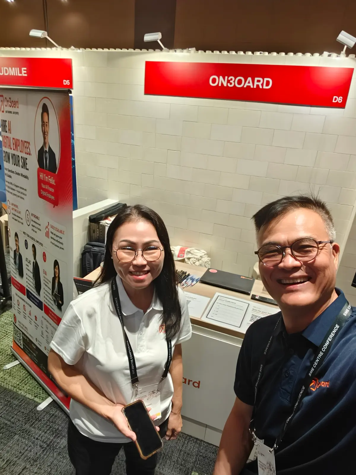 Samantha Lim and Roy Chin smiling in front of the On3oard booth